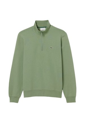 Sudadera de manga larga de color verde claro con un cuello de cremallera de un cuarto y un pequeño logo de cocodrilo en el pecho izquierdo.