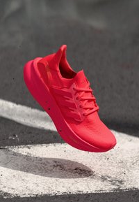 Bright pink athletic shoes with a textured upper, padded collar, and visible lacing system; featuring a lightweight design and defined sole.