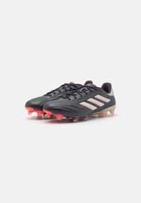 Scarpe da calcio nere con finitura in pelle liscia, caratterizzate da tre strisce bianche, accenti viola e rossi, e tacchetti in gomma sagomati.