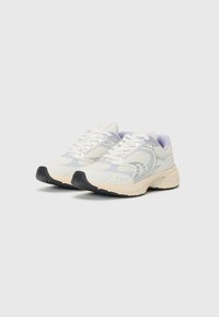Scarpe da ginnastica bianche in rete con accenti viola chiaro, una suola curva e una punta in gomma nera. Presentano lacci e branding sui lati.