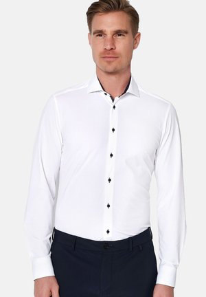 Witte blouse met lange mouwen en een klassieke kraag, voorzien van zwarte knopen en een contrasterende kraagaccent. Gladde stof, getailleerd ontwerp.