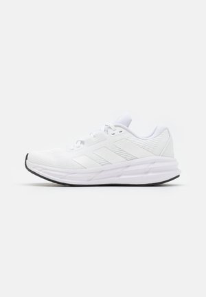 Încălțăminte sport din material mesh alb, cu trei dungi subțiri gri, design elegant, vârf rotunjit și talpă din cauciuc negru.