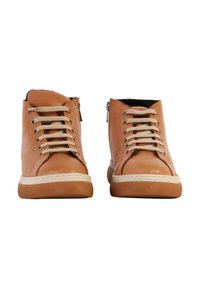 Chaussures montantes en cuir tan avec des lacets beige, fermeture éclair sur le côté, semelle en caoutchouc blanche et accents texturés sur la tige.