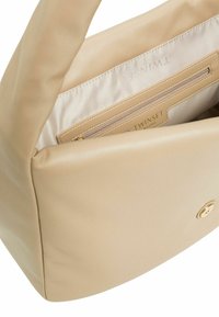 Borsa a tracolla in pelle beige con una texture liscia. L'interno presenta una fodera di colore chiaro e una tasca con zip, logo del marchio impresso sul tessuto.