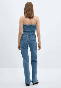 Denim jumpsuit med strapless design, lys blå farve, tætsiddende kjoleoverdel og flagrende ben med baglommer. Glat tekstur hele vejen igennem.