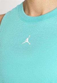 Turkis blå trenings tanktop laget av glatt stoff, med rund halslinning og en hvit Jumpman-logo på venstre brystområde.