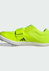 Scarpe da atletica verdi con una tomaia in sintetico liscio, dettagli neri, una cinghia e tacchetti sulla suola per una migliore aderenza.