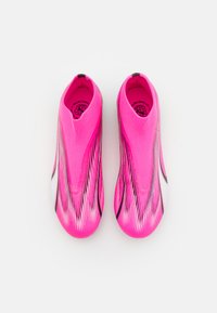 Scarpe sportive di colore rosa brillante con una tomaia simile a un calzino, caratterizzate da una texture liscia, dettagli bianchi e motivi striati neri lungo i lati.