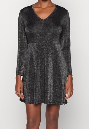 Robes noires à manches longues, décolleté en V et surface texturée chatoyante. Corsage ajusté s'élargissant en une jupe ample.