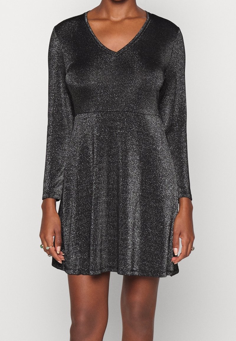 Robes noires à manches longues, décolleté en V et surface texturée chatoyante. Corsage ajusté s'élargissant en une jupe ample.