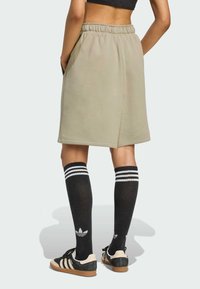 Light brown, knee-length, casual shorts with an elastic waistband and side pockets. Paired with knee-high black socks featuring white stripes.