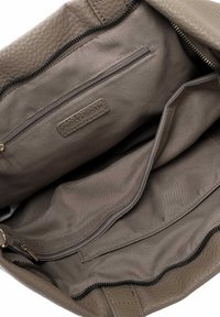 Soft taupe leather handbag interior with multiple pockets, including a zippered compartment and a fabric lining. Textured detail on the bag edges.