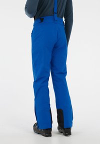 Modré zimné nohavice s nastaviteľnými čiernymi popruhmi. Obsahujú bočné zipsy na manžetách a čierne akcenty pre zvýšenú odolnosť. Hladk�ý povrch.