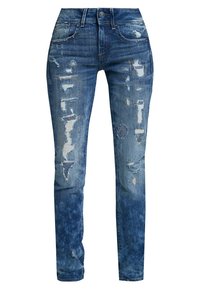Jeans de denim ajustados en diferentes tonos de azul, con detalles desgastados, acentos deshilachados y una cintura de altura media.