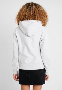 Grau gefütterter Sweatshirt aus weichem Baumwollmix, mit einer Kängurutasche, gerippten Bündchen und Saum, kombiniert mit einem schwarzen Minirock.