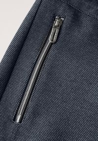 Ciemo niebieski, teksturowany materiał zbliżenie na srebrny zamek błyskawiczny, z gładką zawieszką i kontrastującymi stawami.