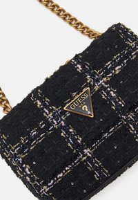 Sorte tweed taske med guldkæde, med en logo-plakette i guld og sort samt et struktureret ternet mønster strøet med pailletter.