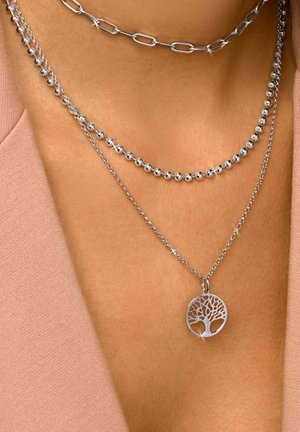 Tre collane d'argento sovrapposte: una con un pendente a forma di albero circolare, un'altra con perle tonde e una terza con maglie allungate.