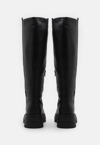 Botas de cuero negro hasta la rodilla con un acabado texturizado, que cuentan con una suela de goma gruesa y cremalleras laterales para facilitar el uso.