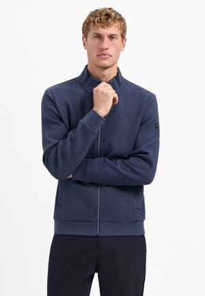 Marineblauwe zip-up jasje met hoge kraag, ribbelzoom en -manchetten, gladde textuur, zijzakken en een logo patch op de mouw.