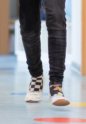 Schoenen bestaan uit een glanzend zilveren ballerina op de ene voet en een zwart-wit geblokte ballerina op de andere, gedragen met zwarte skinny jeans.