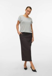 Haut gris à manches courtes associé à une jupe crayon longue à rayures foncées. L'ensemble est complété par des chaussures noires à bout pointu.