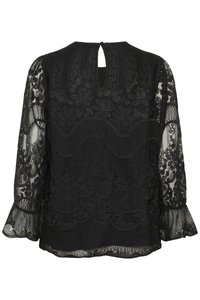 Blouse en dentelle noire avec motifs floraux, manches longues transparentes, poignets froncés et fermeture au dos avec bouton et ouverture en forme de goutte.