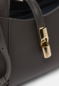 Grijze leren handtas met een gladde textuur, een gestructureerd ontwerp en een gouden metalen slot als opvallend detail.