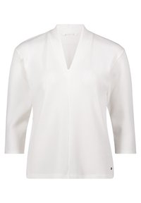 Blusa bianca a coste con scollo a V, maniche a tre quarti e orlo dritto. Presenta un marchio minimale in basso a sinistra.