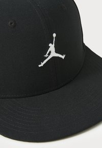 Fekete baseball sapka strukturált dizájnnal és lapos csúccsal. Elülső részén egy fehér hímzett Jumpman logó található.