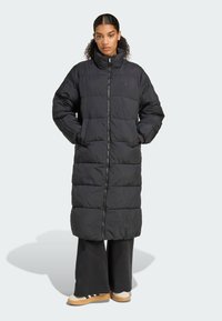 Μαύρο μακρύ μπουφάν με ψηλό γιακά, κλείσιμο με φερμουάρ και οριζόντια καπιτονέ σχέδιο. Διαθέτει πλαϊνές τσέπες και ελαστικές μανσέτες.