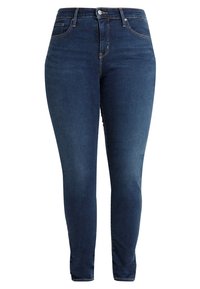 Jeans de denim ajustados en azul oscuro con bolsillos frontales, pasadores para cinturón y cierre de botón y cremallera.