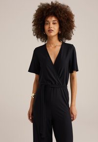 Zwarte jumpsuit met korte mouwen, V-hals en een gestrikt middel. Heeft een textuurstof en een losse pasvorm voor comfort.