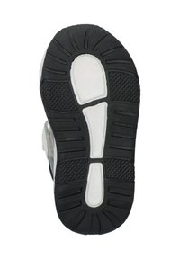 Shoe sole with a textured black rubber surface and white accents. Features ridges for grip and a curved shape at the heel.