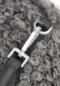Materiale grigio con texture riccia, dotato di una tracolla in pelle nera e hardware metallico argento. Presenta un gancio con marchio inciso.