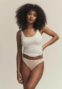 Witte tanktop en huidkleurige slip, beide van gladde stof. De tanktop is aangesloten met een ronde halslijn, terwijl de slip een zachte tailleband heeft.