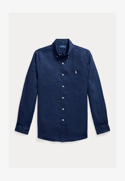 Camisa azul marino de manga larga con botones, cuello abotonado y pequeño logo blanco bordado en el pecho izquierdo.