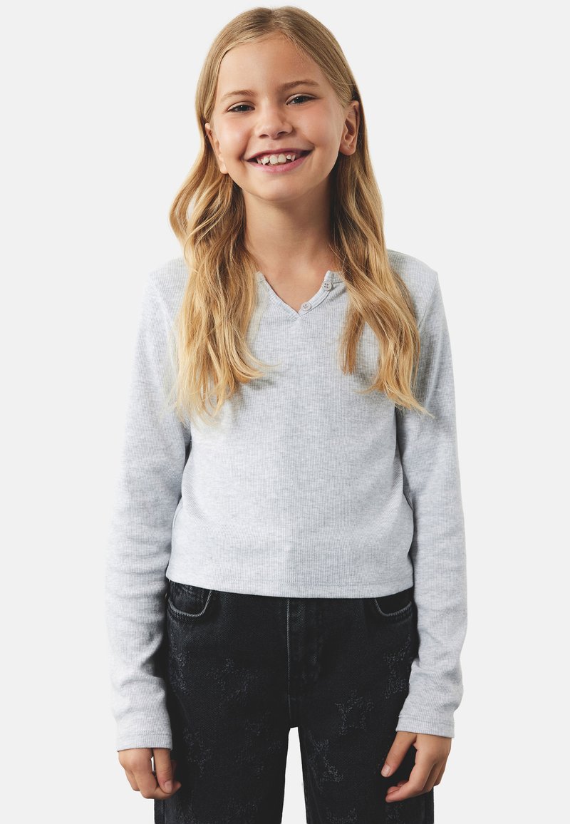Grå langærmet top med ribbet tekstur og V-hals, suppleret med tre små knapper. Sammen med mørke denim jeans med blomstermønster.