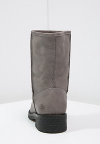 Šedá kožená kotníková bota s jemnou texturou, kulatou špičkou a černou gumovou podrážkou. Obsahuje viditelné švy a logo vyražené na patě.