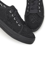 Black lace-up sneakers featuring a textured mesh upper, smooth black rubber sole, and satin laces with metal eyelets.
