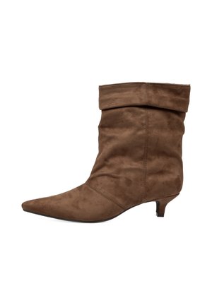 Bota marrón de ante hasta media pantorrilla con punta puntiaguda, caña holgada y tacón corto de tipo kitten, mostrada en perfil lateral derecho sobre fondo blanco.