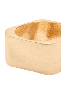 Dekoracyjna misa w kolorze złotym, wykonana z teksturowanego metalu, posiada gładką, zaokrągloną krawędź o lekko nieregularnym, geometrycznym kształcie.