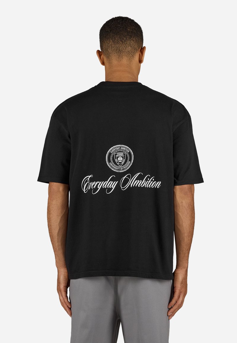 Svart bomull t-skjorte med rund hals. Har et sirkulært logo og teksten "Everyday Ambition" i hvitt på baksiden. Korte ermer, avslappet passform.
