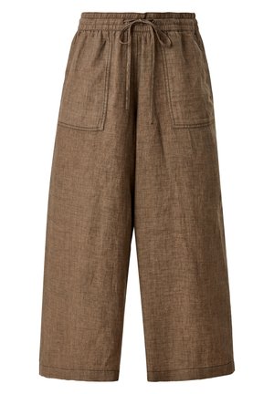 Person wearing loose brown linen wide-leg pants with front pockets, a tucked cream oversized t-shirt, and white chunky sandals.