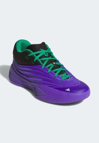 Fialová sportovní obuv s texturovaným syntetickým svrškem, černými akcenty a zelenými tkaničkami. Disponuje aerodynamickým designem a odolnou gumovou podrážkou.