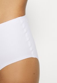High-waisted white bikini bottom made from smooth fabric, featuring flat seams and a clean design with no visible hardware or patterns.