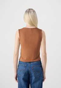 Brązowy prążkowany top na ramiączkach z okrągłym dekoltem, zestawiony z niebieskimi dżinsami o klasycznym kroju i tylnymi kieszeniami.