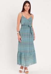 Robe maxi dans un motif géométrique multicolore. Présente des fines bretelles, un corsage ajusté et une jupe fluide à volants. Le tissu semble léger.