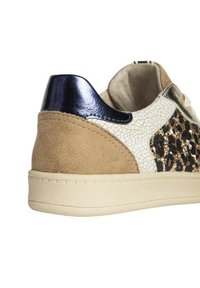 Zapatilla con un talón de ante beige, laterales de cuero blanco agrietado, acentos de estampado animal y un panel trasero azul marino brillante. Suela de color claro.