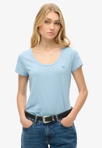 Lichtblauw, T-shirt met korte mouwen en een ronde hals, met een subtiele merklogo. Gecombineerd met high-waisted denim jeans en een zwarte riem.